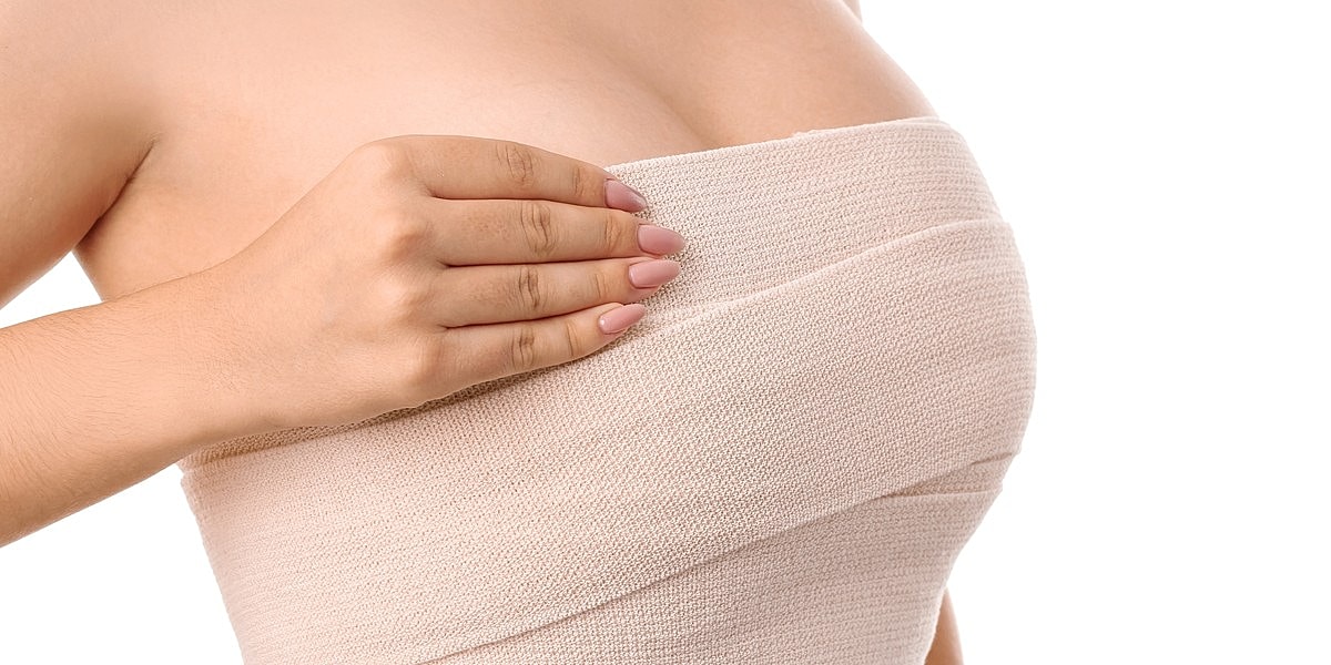 Woman adjusting a skin-colored band around torso.