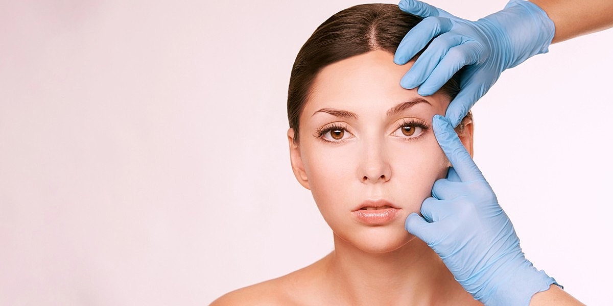 Woman receiving facial treatment with gloved hands