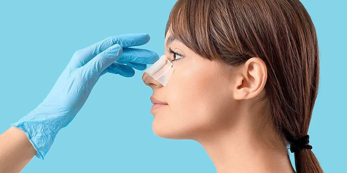 Applying a bandage to a woman's nose.