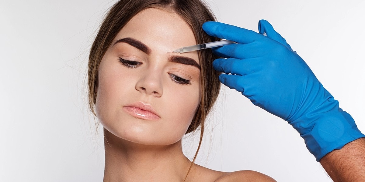Patient receiving eyebrow treatment from professional.