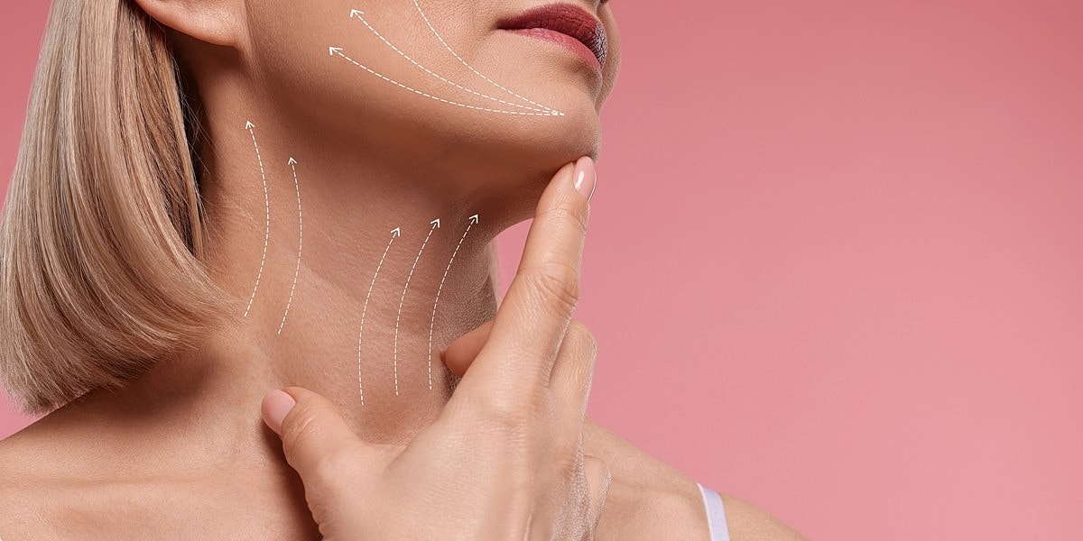 Woman modeling skincare techniques on pink background.