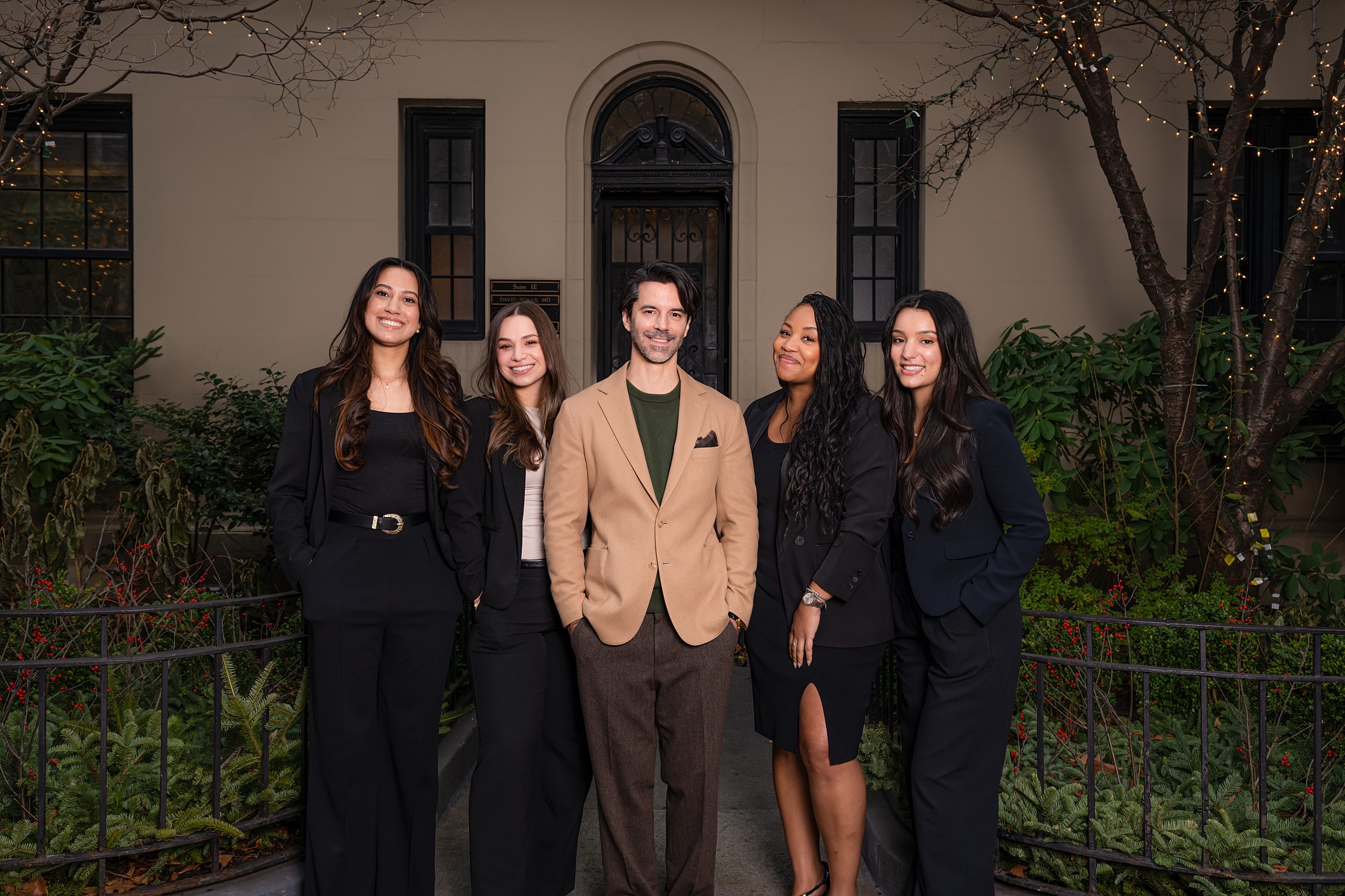 Group of professionals posed outdoors in stylish attire.