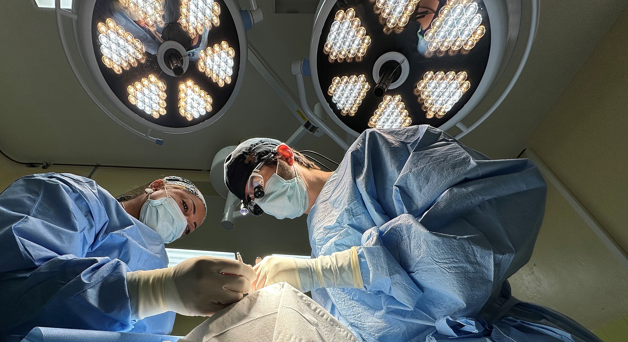Surgeons operating under medical lights in surgery.